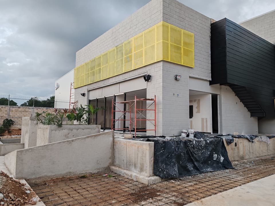 Fachada comercial con celosía metálica amarilla y negra
