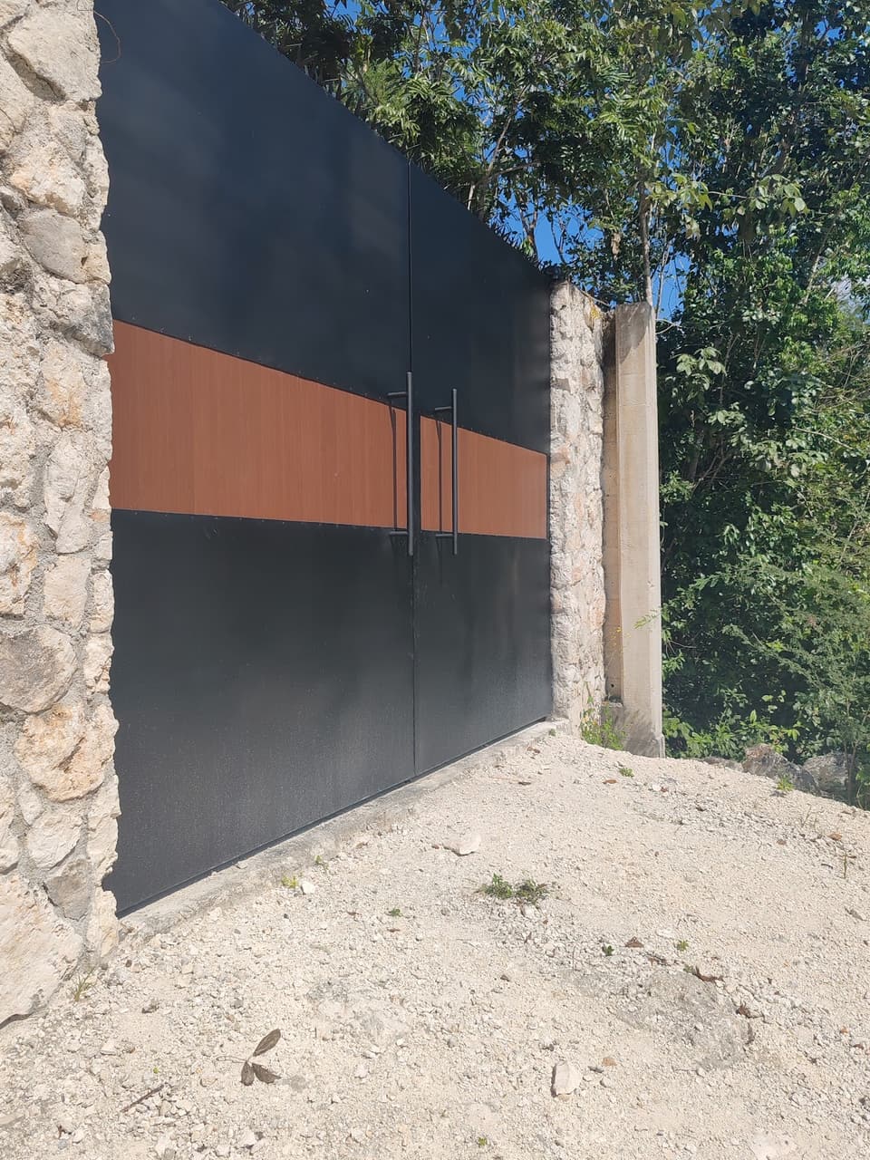 Portón corredizo de acero negro con franja de madera